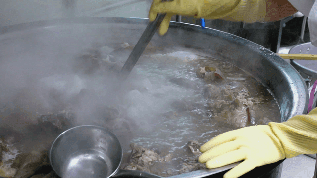 Boiling meat in a large pot with steam