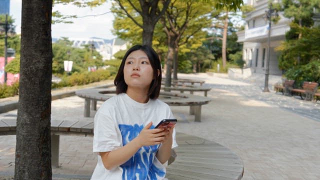 Woman sitting on a bench using her phone