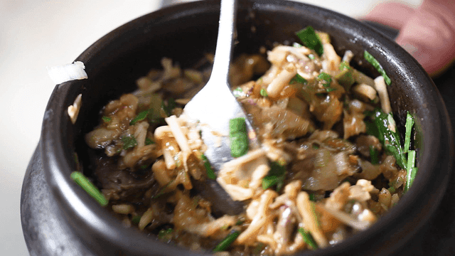 Spoon mixing soybean paste into stone pot rice