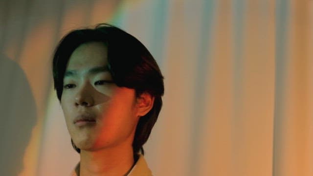 다채로운 조명 속에서 웃음을 참는 남성