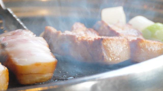 Pork belly sizzling on a grill