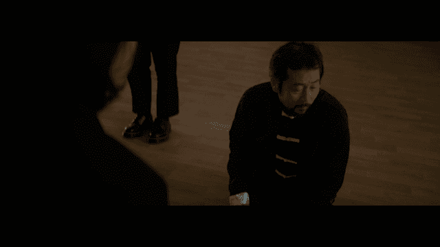 나무 바닥에 무릎 꿇은 중국 전통의상을 입은 남자