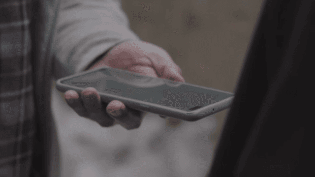 사람이 다른 사람에게 스마트폰을 건네는 장면