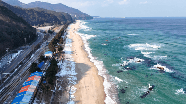 Scenic beach with waves and train tracks