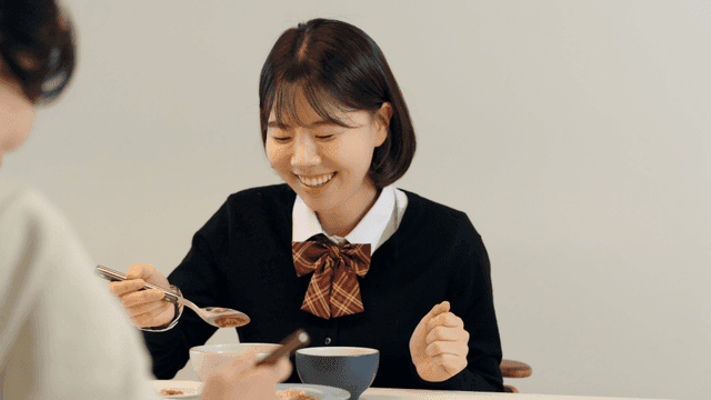 High school daughter eating meal with her mother