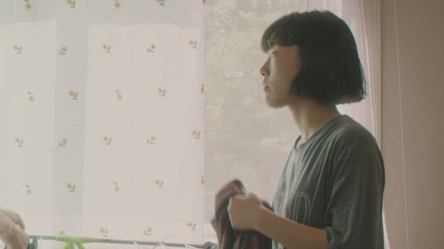 아침에 창문 옆에서 빨래를 널고 있는 여자