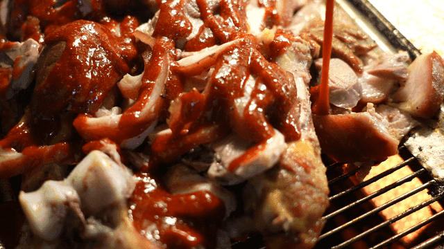 Pork trotters topped with spicy sauce on grill