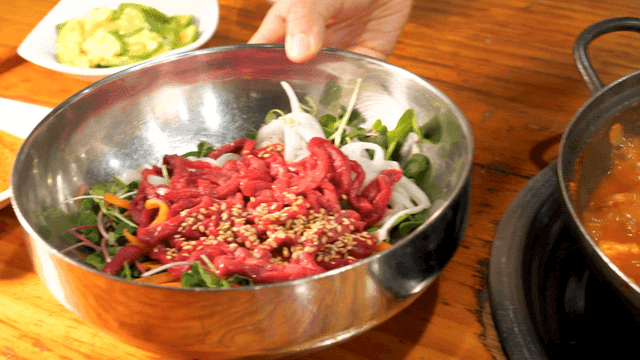 Kimchi stew and yukhoe bibimbap on wooden table
