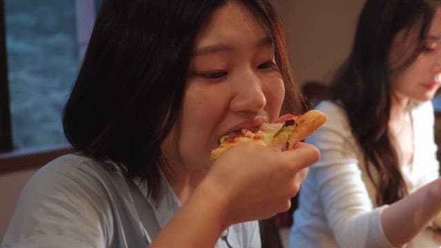 Two women enjoying pizza indoors