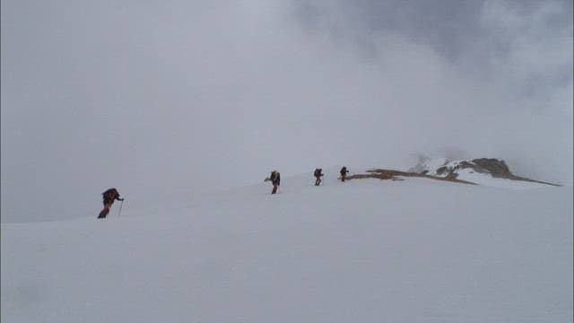 Hikers Ascending Snow-Covered Mountain Slope