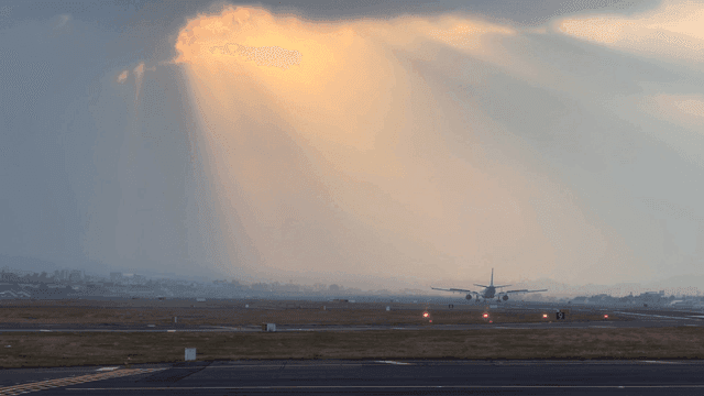 Airplane on runway under cloudy sky