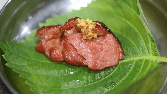 Whole grain mustard on meat wrapped in perilla leaves