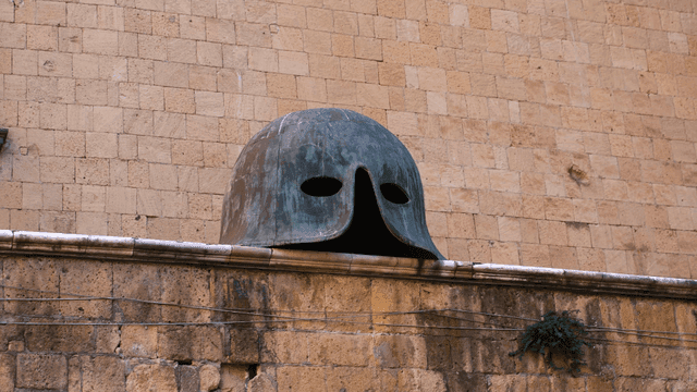 Large bronze helmet on stone wall