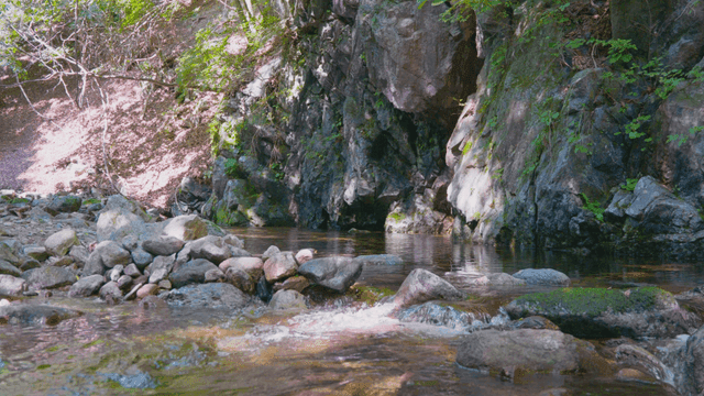 바위 절벽 아래 돌 사이로 흐르는 고요한 시냇물