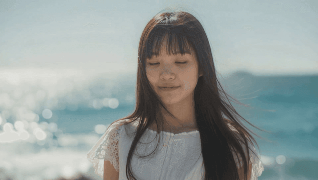 바다 옆에서 정면을 보고 미소 짓는 젊은 여성