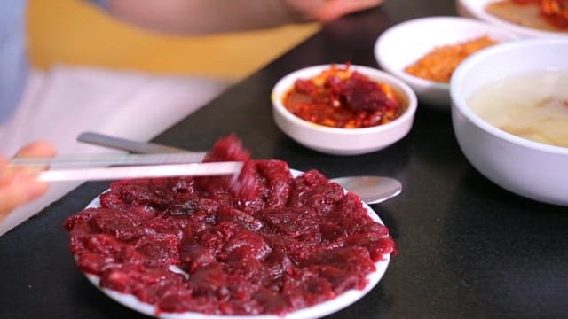 Delicious sliced raw bottom round steak dipped in seasoning sauce