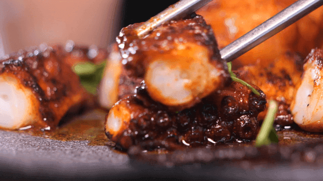 Grilled fatty octopus legs picked up with chopsticks