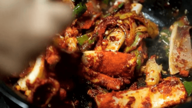 오징어, 채소를 볶은 냄비에 고춧가루를 넣는 모습