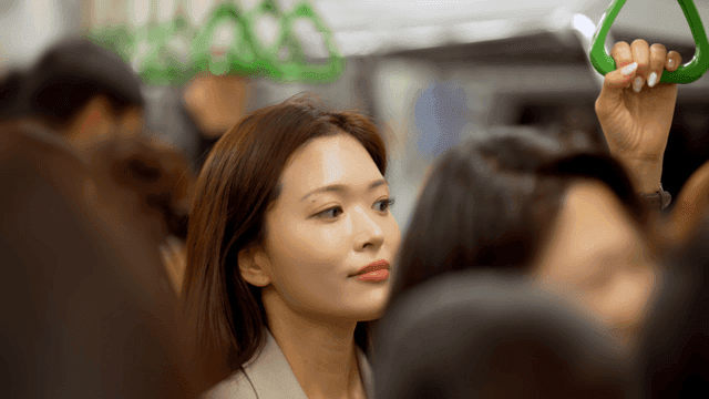 Woman holding onto handrail amidst crowded subway people
