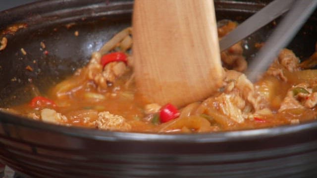 팬에 남은 요리를 나무주걱과 가위로 휘젓는 모습