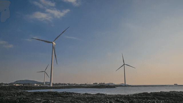 Wind turbines by the sea at sunset