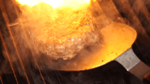 Beef patty flipped over rising flames