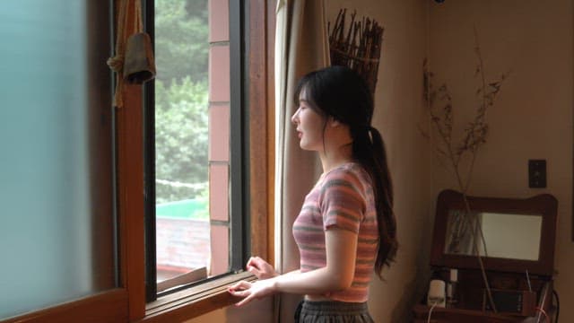 Woman looking out the window in a cozy room