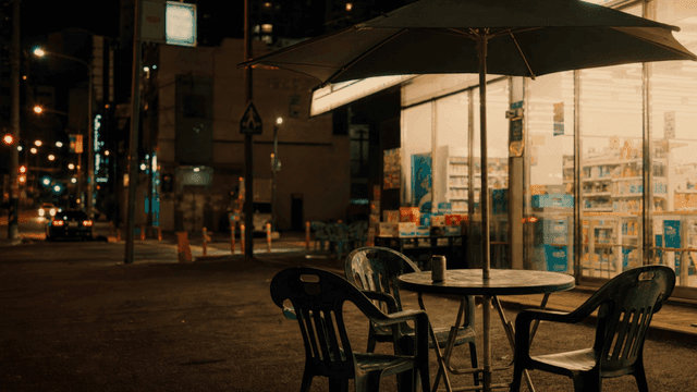 Outdoor tables with beverage cans placed in front of city convenience store at night