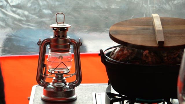 Lighting the camping lantern next to the pot with food