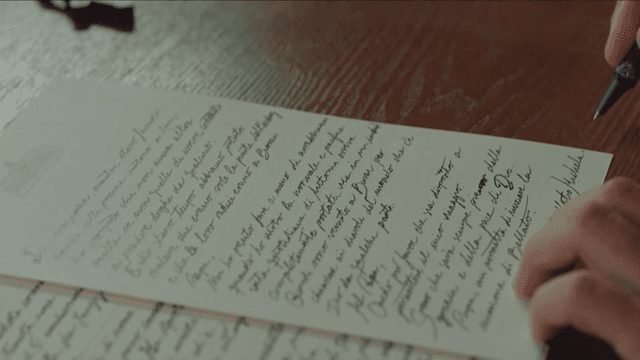 나무 테이블 위에서 편지를 쓰는 사람