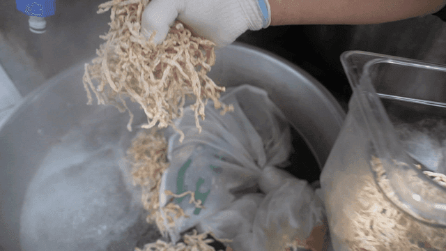 대형 솥 안 뜨거운 육수에 넣어지는 무말랭이