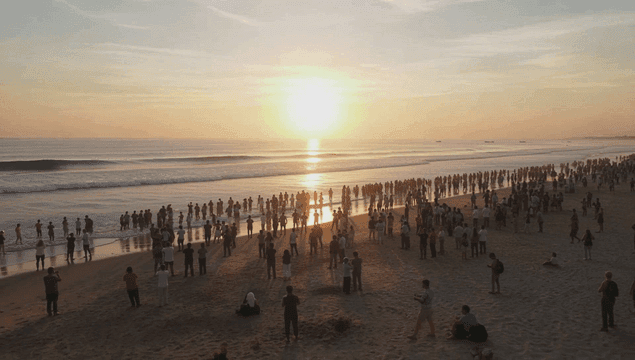 해변에 모인 군중과 일출