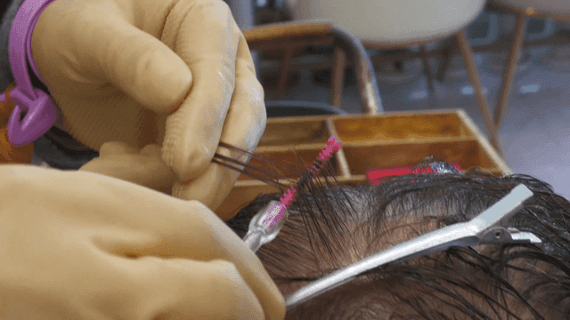 Hairdresser giving perm at beauty salon