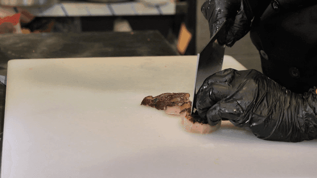 Chef slicing mushrooms long and delicately on cutting board