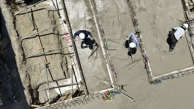 건설 현장에서 콘크리트를 고르는 작업자들