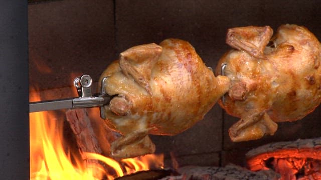 Wood-fired whole chicken roasting over open flames