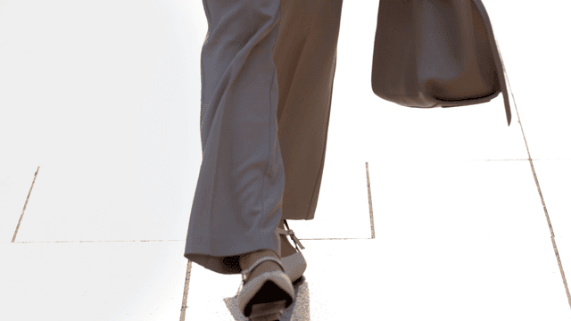 Office worker walking on sunlit sidewalk