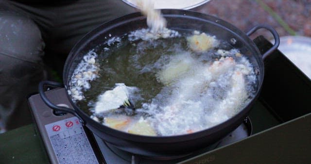 Preparing fried food outdoors with a portable stove