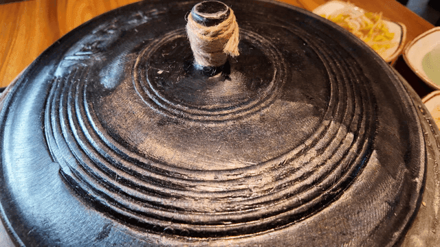 Black pot with a lid on a wooden table