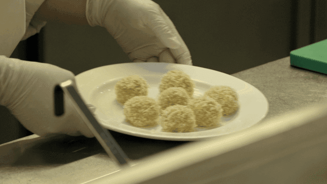 Chef preparing breaded balls on a plate