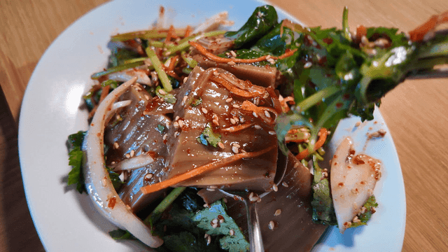 Seasoned acorn jelly piled onto spoon with chopsticks
