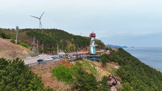 Coastal road with a lighthouse and wind turbine