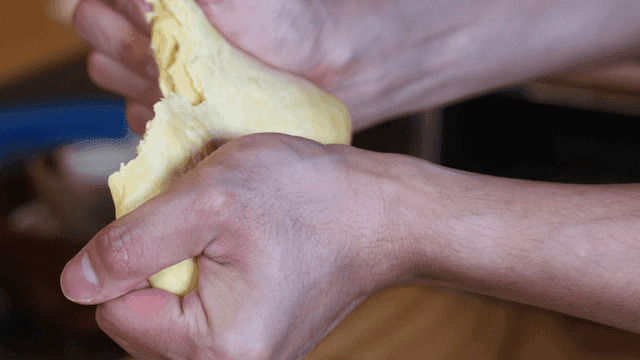 Hands tearing dough in kitchen