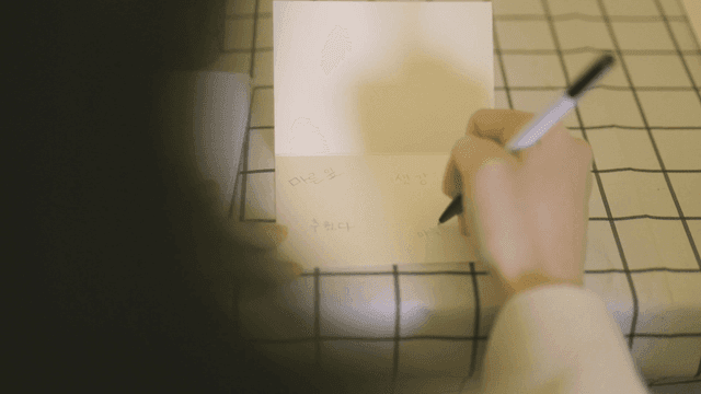 Person writing letter on table