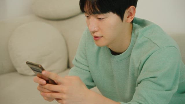 소파에 앉아 스마트폰을 사용하는 남자