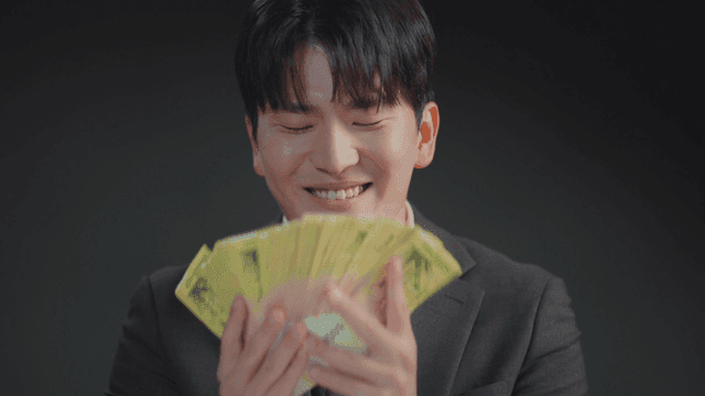 정장을 입은 남자가 돈다발을 냄새 맡는 모습
