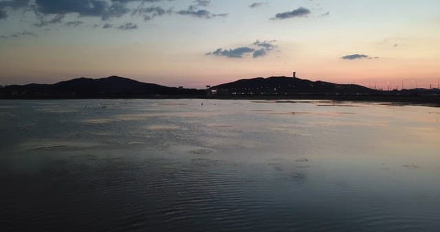 Sunset over a tranquil sea with distant hills