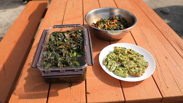 나무 테이블 위의 시금치로 만든 장아찌와 무침, 계란말이