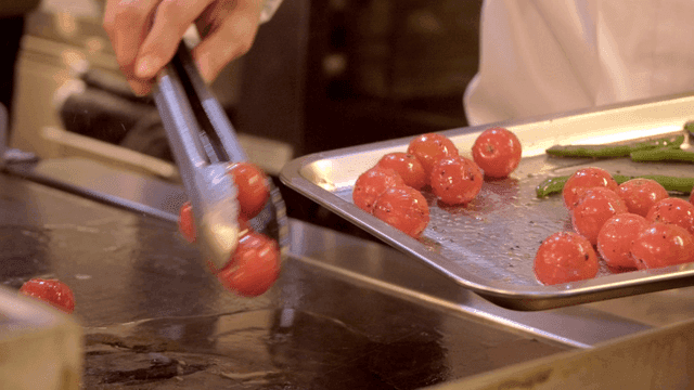 Chef grilling cherry tomatoes on griddle