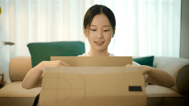 Woman opening delivery box on sofa